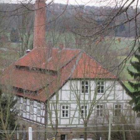 Bild vergrößern: Wassermühle Henneckenrode mit Schorstein des Zementwerks