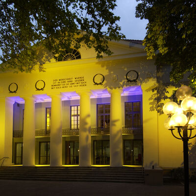 Das gelb und lila beleuchtete Theater für Niedersachsen (der Haupteingang).